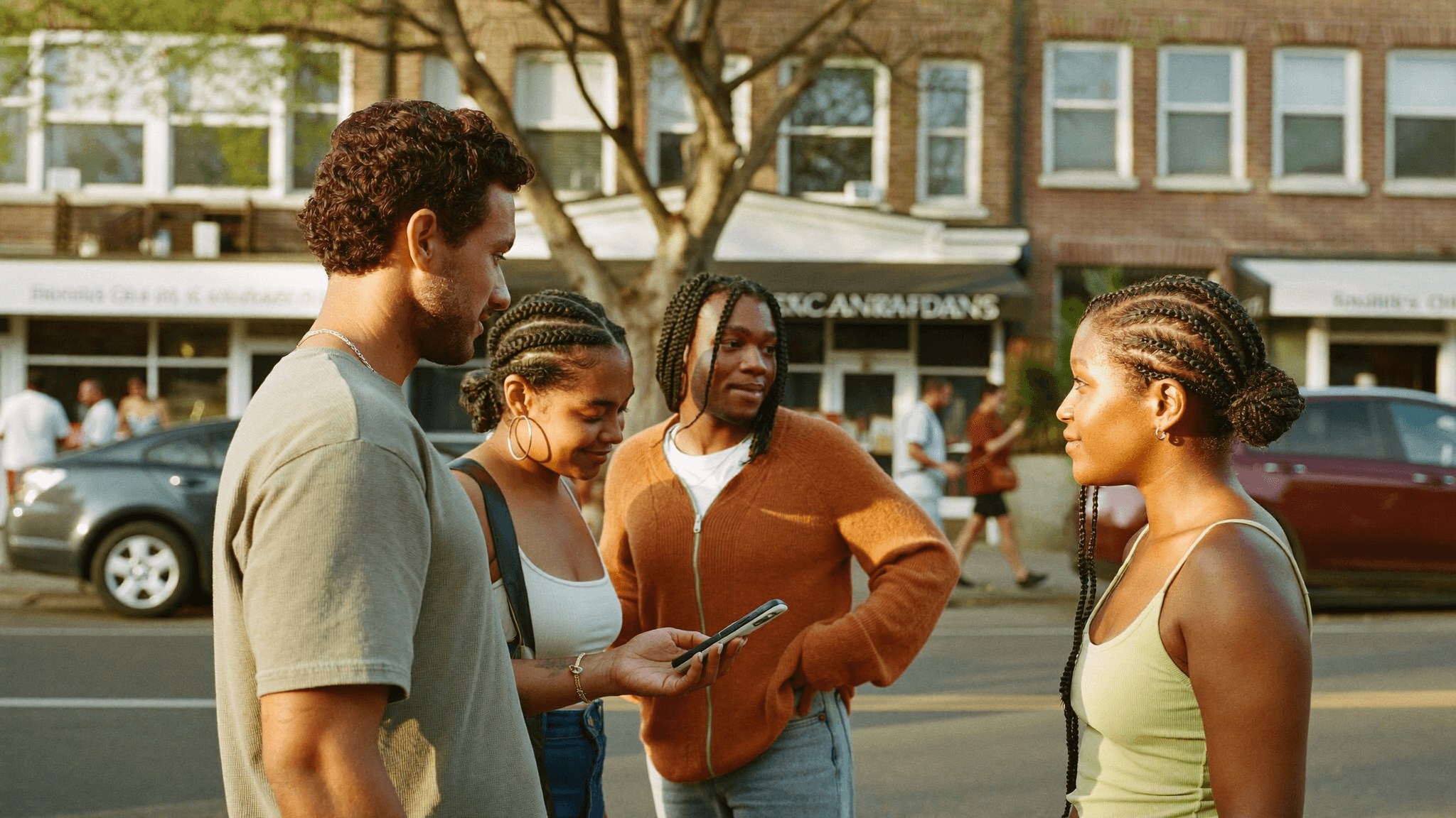 South African friends looking at a phone together on a warm suburban street